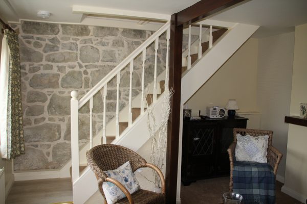 Lounge with exposed stone wall and staircase